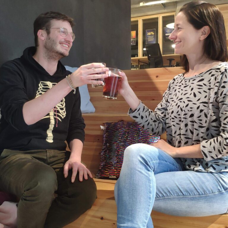 Mann und Frau trinken Cascara Tee und stoßen mit ihren Gläsern an